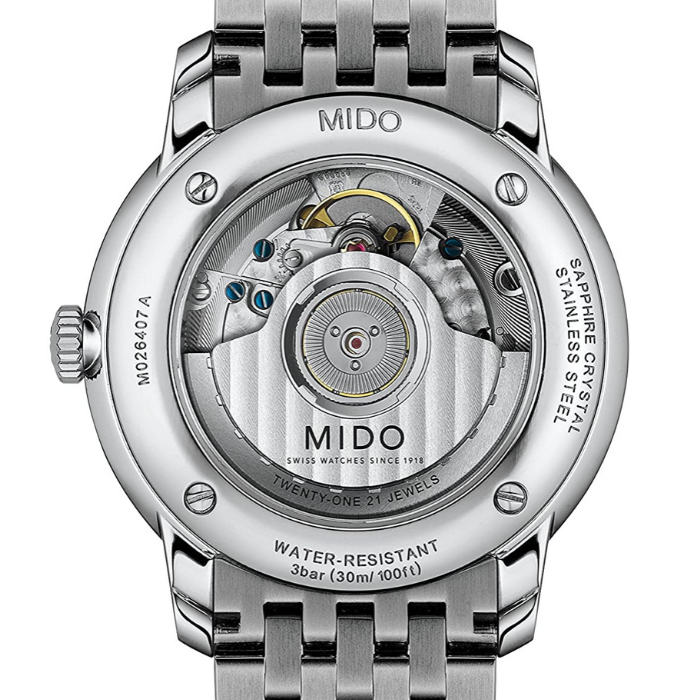 Orologio da uomo solo tempo automatico della collezione Mido Watches modello Baroncelli Heritage Cassa in acciaio inossidabile con diametro di 39 mm, spessore di 7,25 mm e fondello a vista che lascia intravedere il meccanismo automatico dell'orologio Quadrante di colore bianco con indici e lancette di colore nero e datario a ore 3 Vetro zaffiro antigraffio con trattamento antiriflesso Movimento automatico Mico calibro 1192 su base ETA 2892A2 Resistente all'acqua fino a 30 metri (3 bar) Cinturino in acci