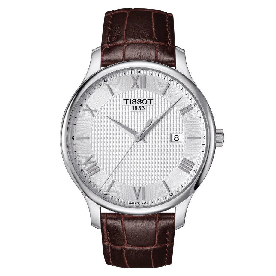Orologio da uomo solo tempo al quarzo della collezione T-Classic Tissot modello Tradition Cassa in acciaio inossidabile con diametro di 42 mm e spessore di 7,5 mm Quadrante color argento con disegno quadrettato, indici romani e lancette color argento e datario a ore 3 Vetro zaffiro antigraffio Movimento svizzero al quarzo calibro ETA F06.111 Resistente all'acqua fino a 30 metri (3 bar) Cinturino in pelle marrone con stampa effetto alligatore e chiusura a farfalla Codice prodotto: T0636101603800